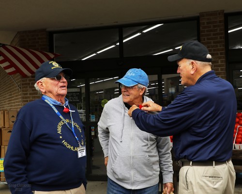 Post 370 Legionnaire Bill Edwards pins on a poppy as Post 370 Legionnaire Dr. Carter Davis looks on.